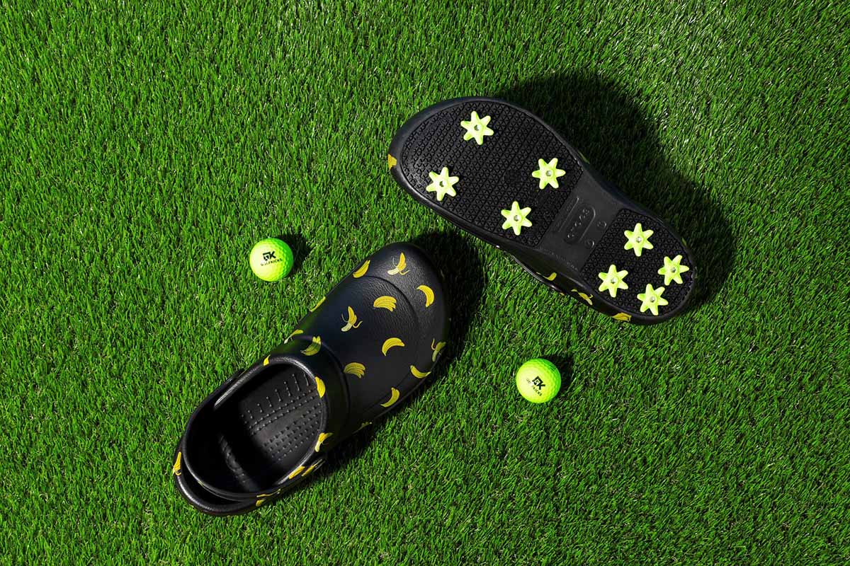 Black Crocs customized with Golfkicks cleats on a green golf course.