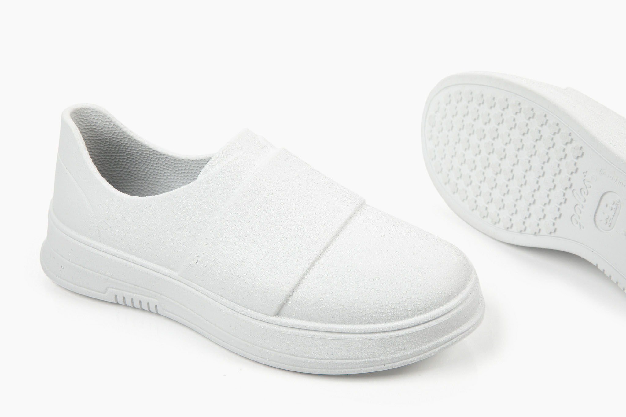 White slip-on shoes displayed against a white background, with one shoe slightly angled to show the sole.